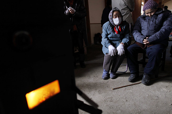 24 hours in pictures: An elderly couple take refuge around a wood stove, Japan