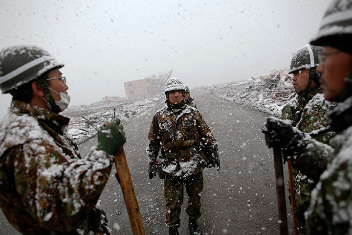 Japan aftermath: An army officer instructs his team in the residential area of Otsuchi as heavy snow falls