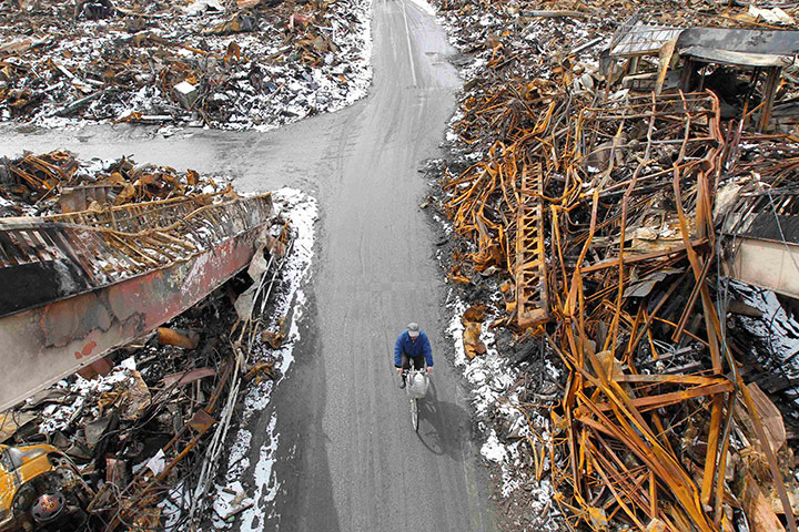 Japan aftermath: A man rides a bicycle at an area hit by earthquake and tsunami in Kesennuma