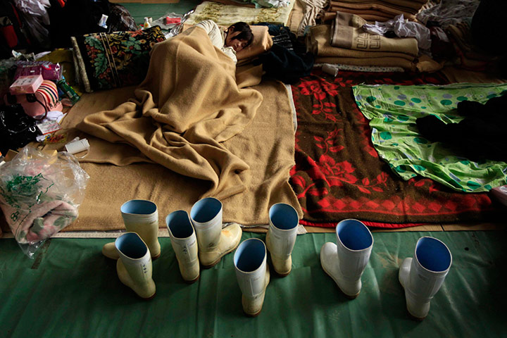 Japan aftermath: A young woman rests in a school gymnasium being used as a refuge centre in Ofunato