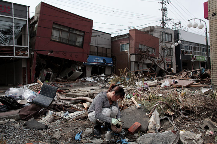 Japan aftermath: A woman sifts through the rubble of her home in Kesennuma