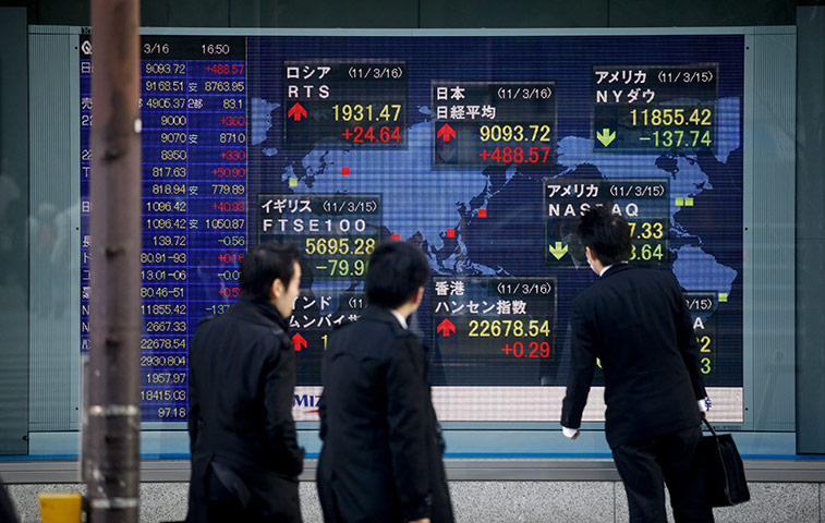 Week in Business: People look at a board showing the Stock Exchange as Nikkei stocks rose