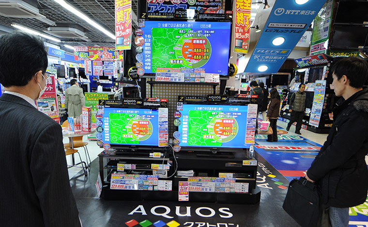 Week in Business: Tokyo residents watch a television news report on radioactive exposure