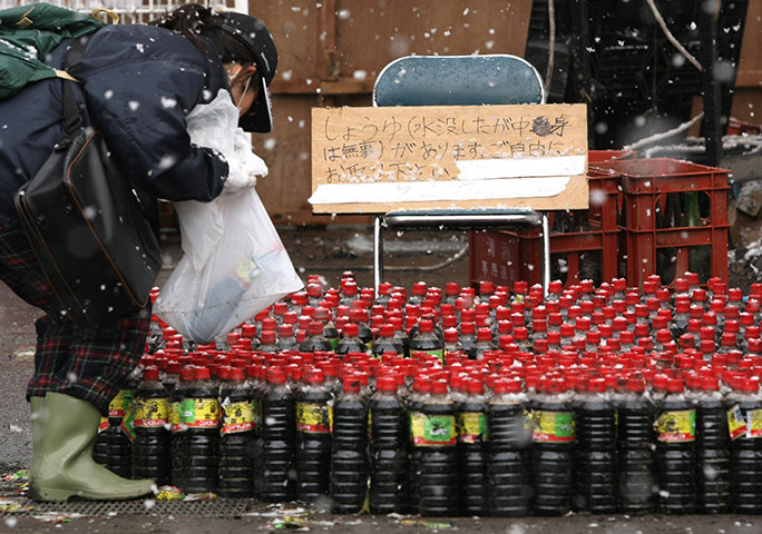 Japan aftermath: A woman picks up a bottle of soy sauce at Kamaishi city, Japan