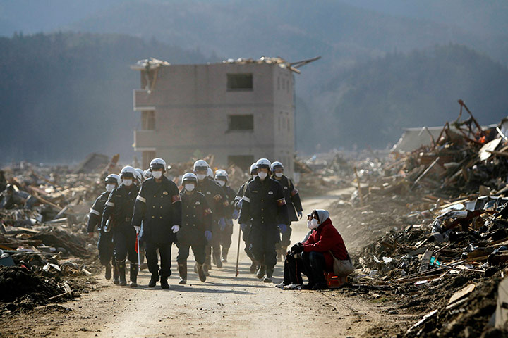 24 hours in pictures: Emergency workers walk past survivors in Rikuzentakata, Japan