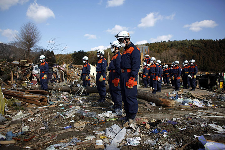 Japan Earthquake: A group of rescue workers observe a minutes silence in Rikuzentakata