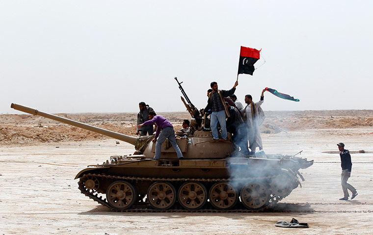 Libya: Rebels wave a Kingdom of Libya flag as they ride on a tank in Ajdabiyah