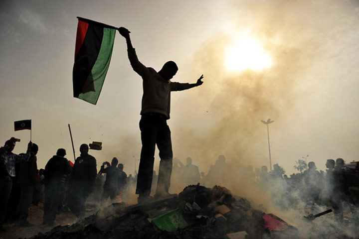 Libya unrest continues: A Libyan protester stands on top of a pile 