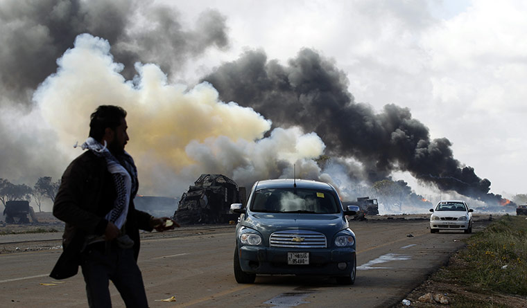 Libya airstrikes: A rebel fighter looks at burning vehicles after an air strike
