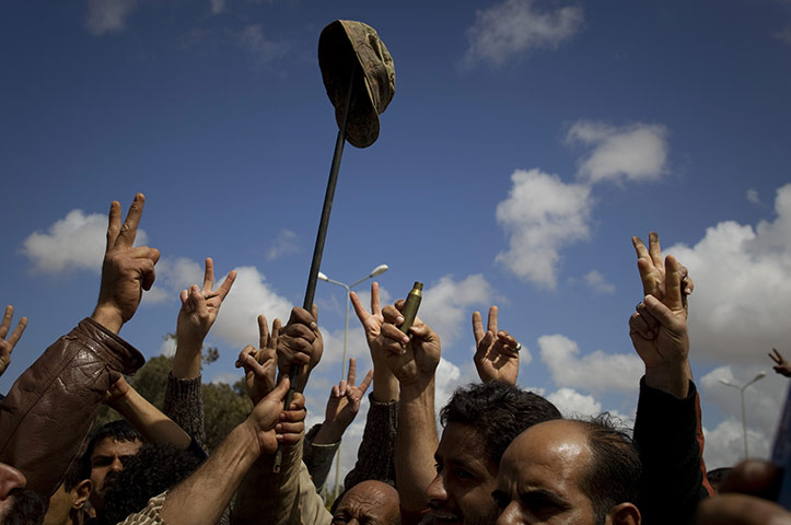 Libya airstrikes: Libyan rebels celebrate with a soldier's army cap 