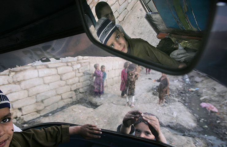 24 hours in pictures: An Afghan refugee boy looks on while sitting in a rickshaw