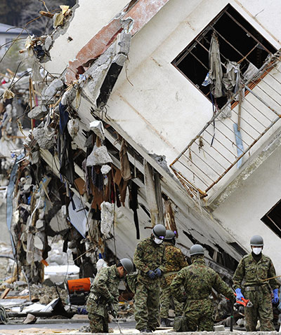 Japan salvage: Japanese soldiers remove debris near damaged buildings in Onagawa