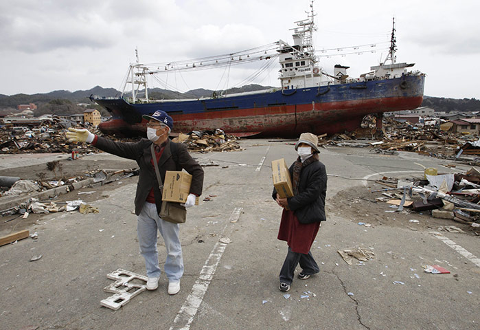 Japan salvage: Residents carry boxes of food in front of a fishing trawler in Kesennuma