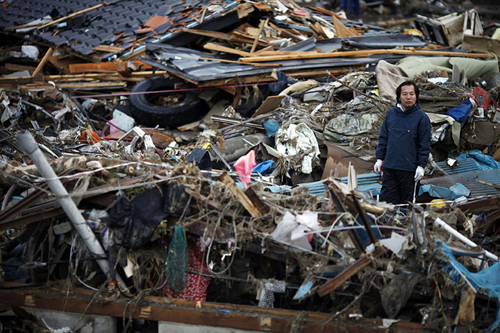 Japan salvage: A man inspects the damage as he tries to retrieve belongings in Otsuchi