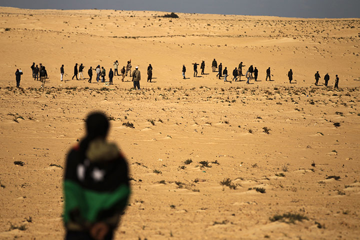 Libya chaos: A Libyan rebel covered with the rebellion flag looks at a column of rebels