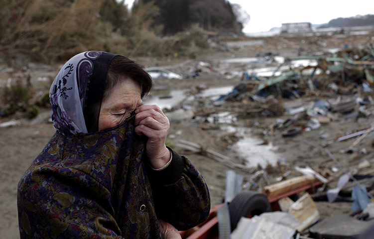 24 hours: A woman reacts as she stands next to her house in Motoyoshi, Japan