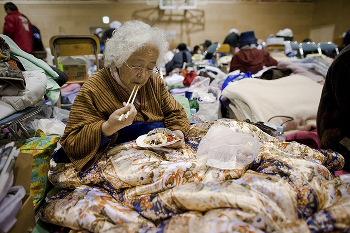 Japan survivors: An elderly tsunami survivor eats dinner under a blanket, Japan