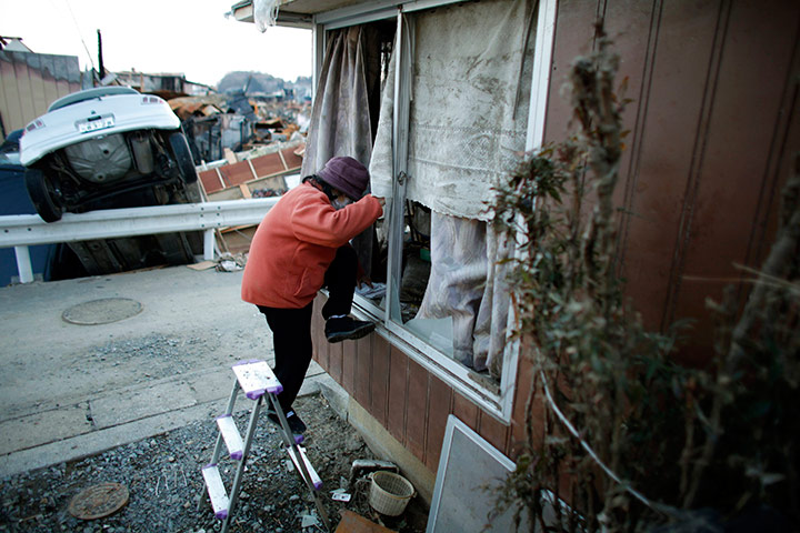 Japan survivors: A woman enters her house which was damaged by in Kesennuma town