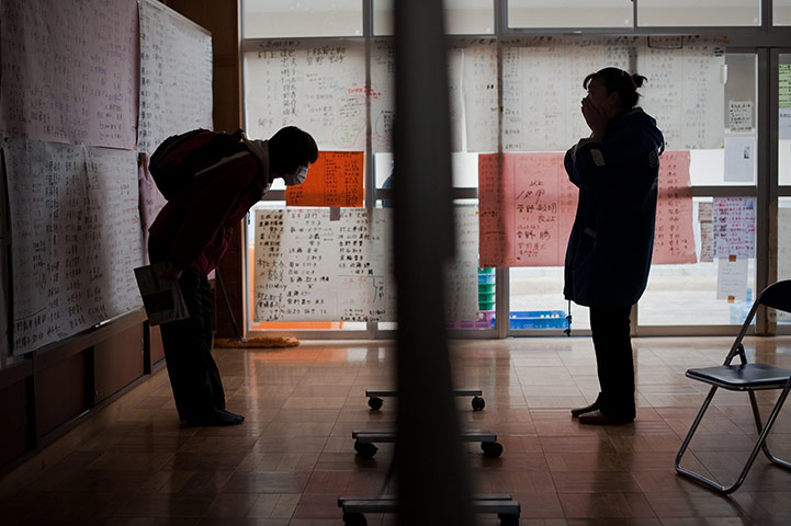 Japan aftermath: People read messages displayed on the wall of a relief centre