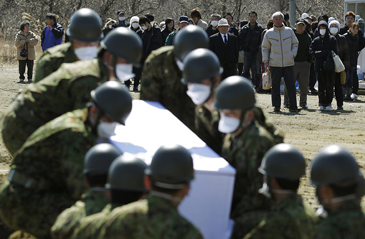 Japan aftermath: Bereaved family members at a temporary mass grave in Higashi-Matsushima