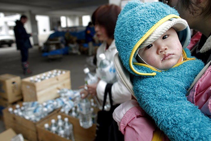 Japan Eartquake: Fukushima crisis : A woman holds a baby as collecting mineral water