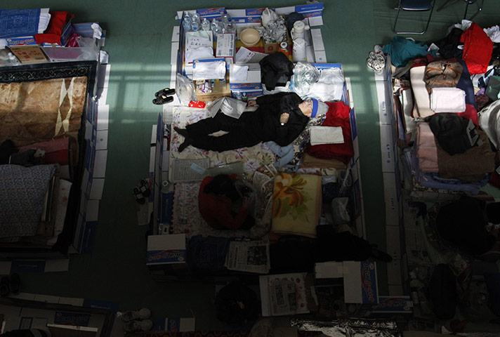 24 hours: Ofunato, Japan: An elderly man sleeps in a gym at a junior high school