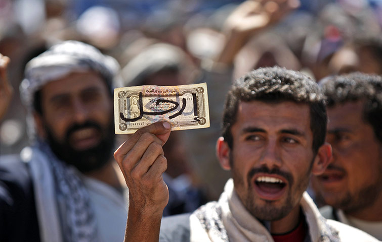 Yemen protests: an anti-government protester holds local currency as a symbol of poverty 