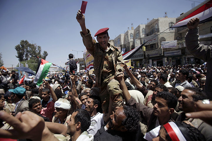Yemen protests: a Yemeni army officer lifted by protesters holds up a red card 
