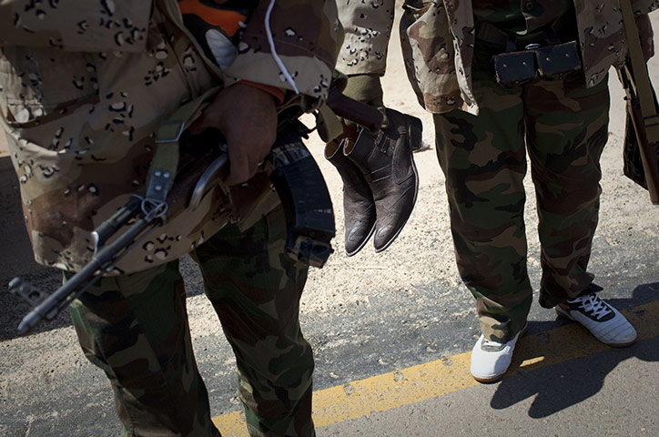Libya conflict continues: A rebel fighter carries his boots after he was supplied with trainers
