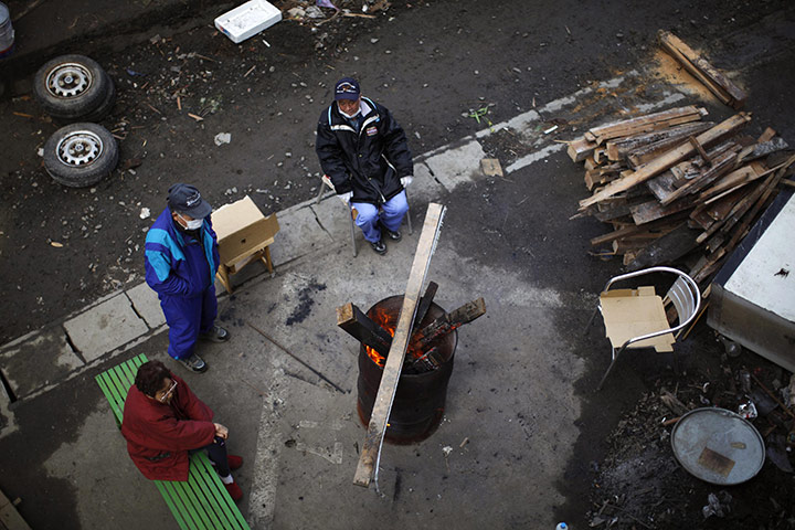 Japan : People sit next to a fire in an area destroyed by the tsunami in Kamaishi