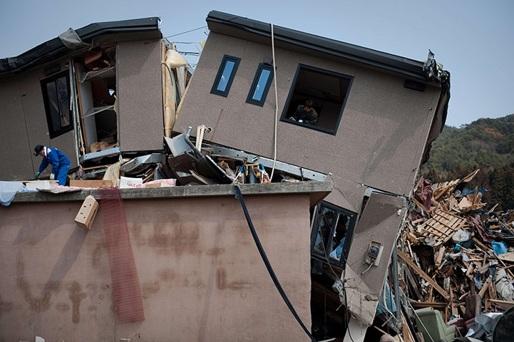 24 Hours: A resident looks out from his damaged home two weeks after the quake