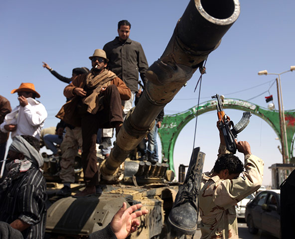 Ajdabiya seized by rebels: Libyan rebels celebrate on a tank destroyed by the coalition