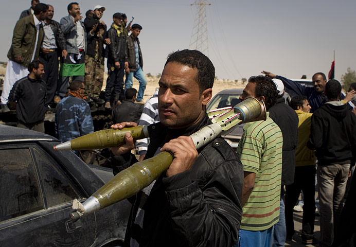 Ajdabiya seized by rebels: A Libyan rebel carries rocket propelled grenades after taking the city