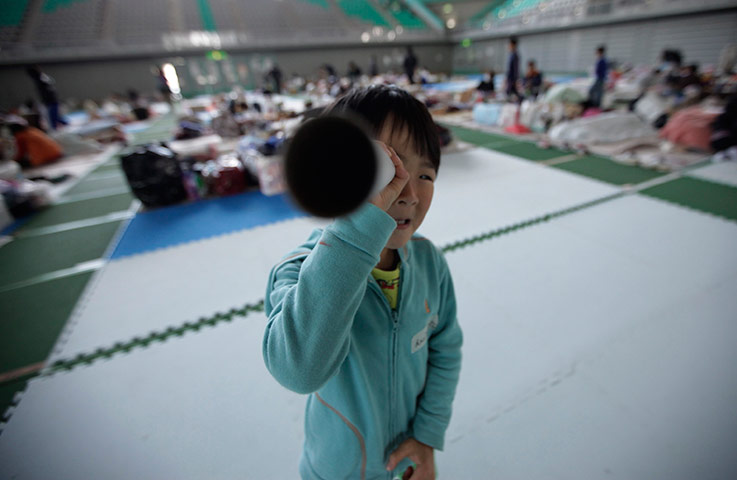 24 hours in pictures: Child evactuaee plays in refuse centre, Yamagata, Japan