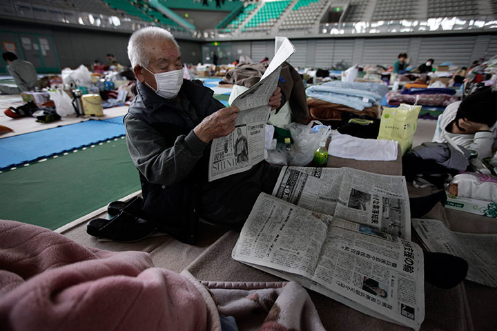 Japan aftermath: An evacuee reads newspapers in a gymnasium in Yamagata, Japan 