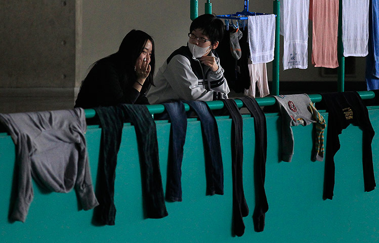 Japan aftermath: Evacuees chat near laundry in a gymnasium in Yamagata