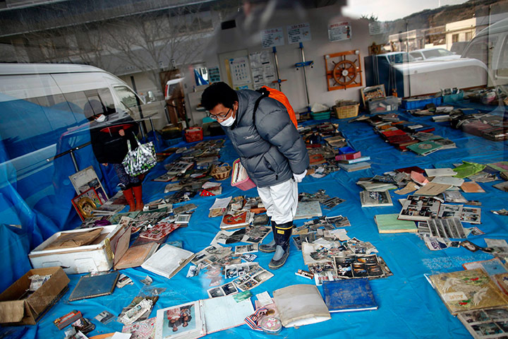 Japan aftermath: A man looks for family photos in a room of personal belongings salvaged