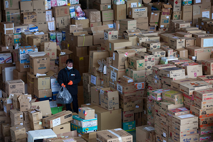 Japan aftermath: A man walks through boxes of emergency relief supplies in Onagawa, Japan