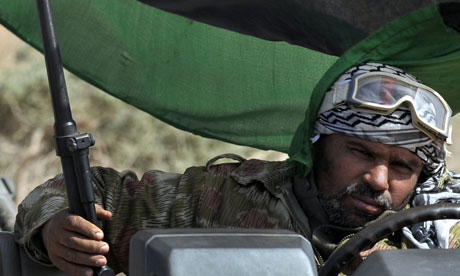 A Libyan rebel fighter sits in his vehicle as rebel forces move towards Muammar Gaddafi's home town