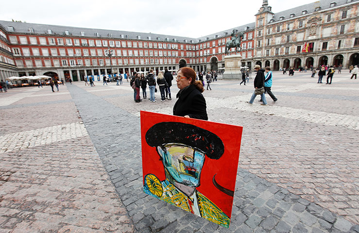 Graeme Robertson in Spain: A woman carries a painting across the Plaza Mayor 