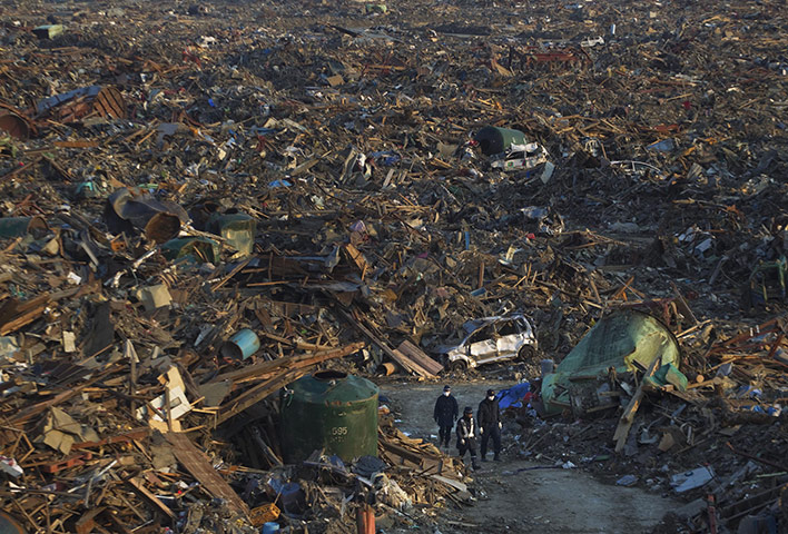 japan: Japanese police walk along a path through the rubble of Rikuzentakata