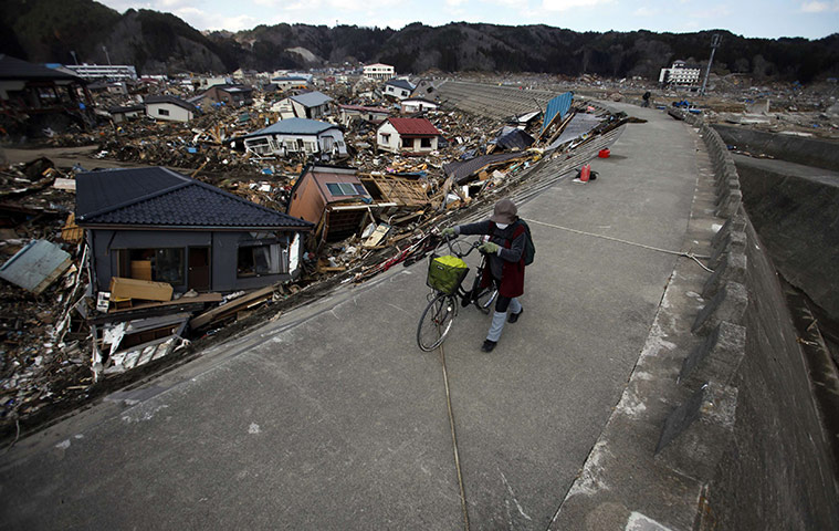 japan: A woman walks with her bicycle on a seawall in Taro town