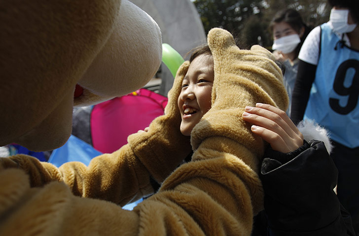 japan: A young girl is entertained by costumed clown at a shelter in Fukushima