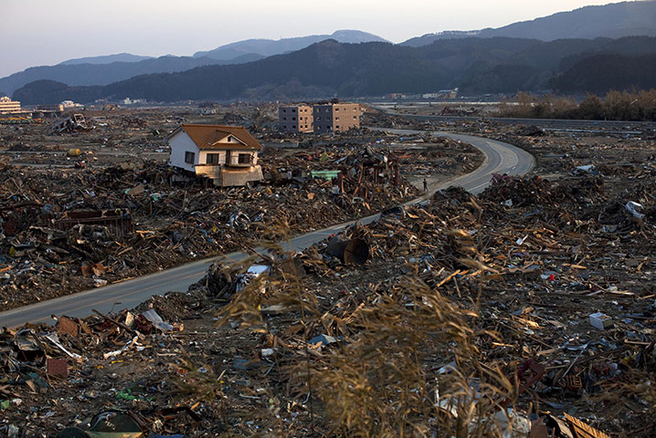 japan: A man walks along a road through Rikuzentakata 