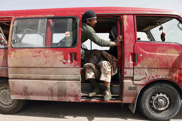 Conflict in Libya: A rebel assists an injured comrade after clashes with pro-Gaddafi forces