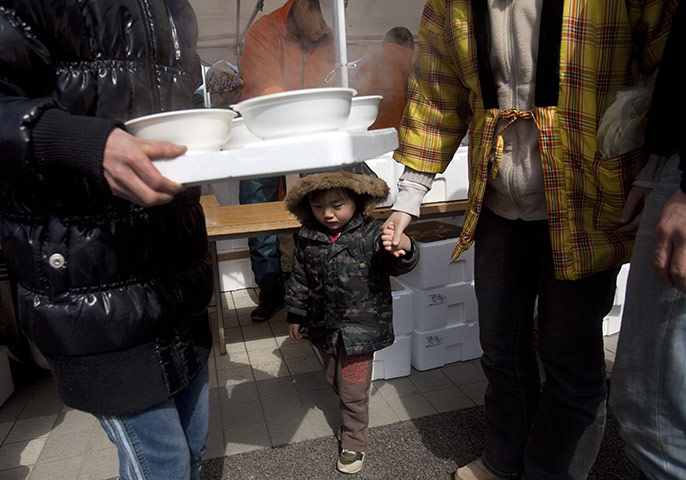 From the agencies: Evacuees receive soup in a line at a shelter in Minamisanriku 