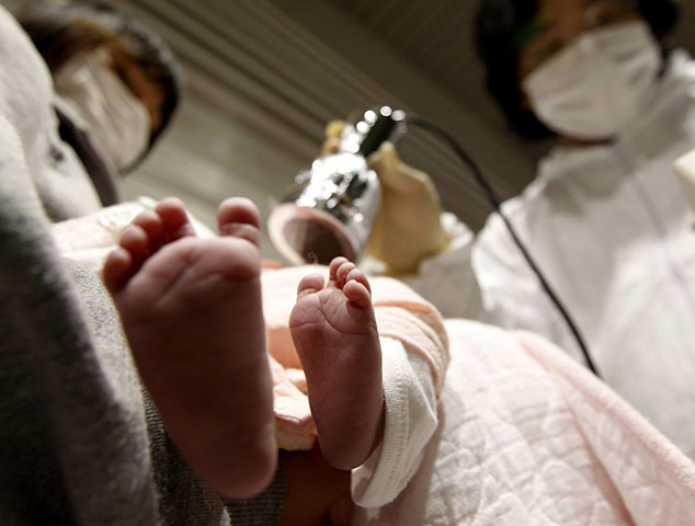 24 hours in pictures: A two-week-old baby is tested for possible nuclear radiation in Japan
