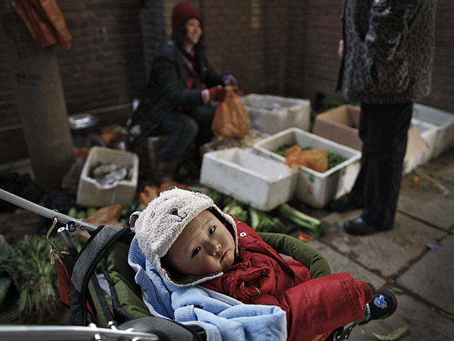from the agencies: A baby sits in a buggy at a vegetable stall