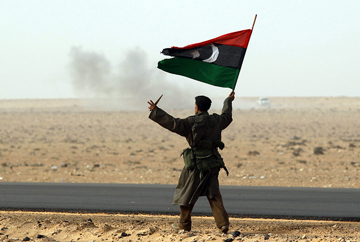 libya unrest continues: A rebel fighter holds a Kingdom of Libya 