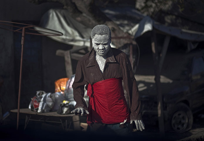 24 hours in pictures: Port-au-Prince, Haiti: A beggar covered with white paint walks along 